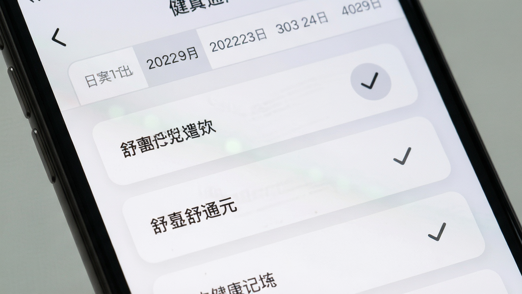 舒真通元应用内健康记录界面特写,画面主体为手机屏幕局部放大,显示日期选择条与多个可点选的记录条目,条目以卡片形式纵向排列,布局规整留白充足,风格为简约浅灰质感,细节上选中状态有柔和底色变化,画质清晰干净,无多余元素