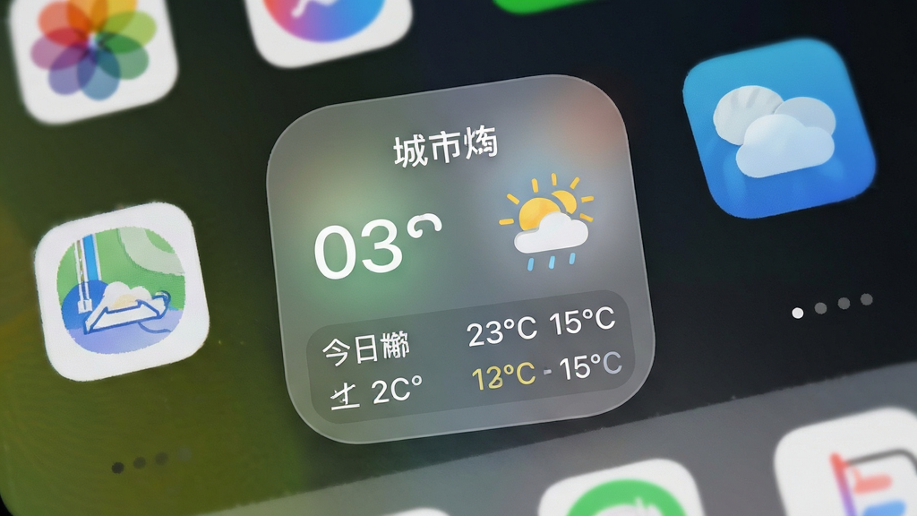 天气预报应用桌面小组件展示,手机桌面背景上放置一个方形天气组件,组件内显示城市名、当前温度、天气图标与今日温度区间,组件风格为圆角卡片配半透明磨砂效果,周围有其他应用图标点缀,布局自然,细节清晰,画质高清,画面干净,无多余元素