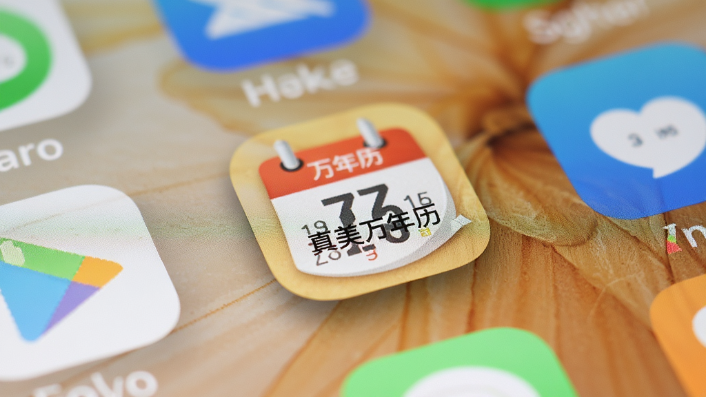 真美万年历应用在手机桌面上的图标特写,图标为圆形日历样式带有真美万年历字样,周围为手机桌面其他应用图标,背景虚化,风格为真实手机截图质感,细节包括图标阴影、桌面壁纸淡雅、图标排列整齐,画质高清,画面干净,无多余元素