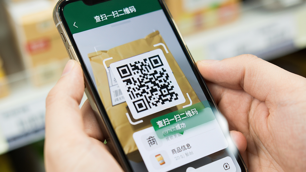主体为手持手机扫描商品包装上的二维码,屏幕显示