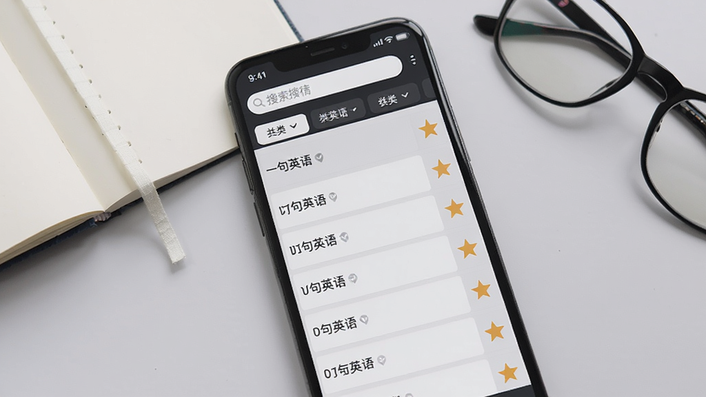 һ��Ӣ��APP���ղظ�ϰ����չʾ������Ϊ�ֻ����棬��Ļ����ʾ���������еľ����б���ÿ����Ŀ�Ҳ������Ǳ�ǣ�������������ͷ���ɸѡ��ǩ������Ϊǳ��ɫ���棬����һ�������ıʼǱ����۾����Ű����࣬����Լ���񣬻���ɾ����޶���Ԫ�أ�ͼƬ�����ֱ�ע