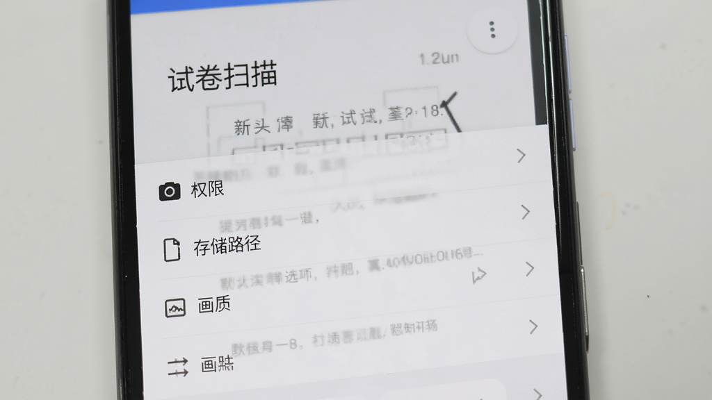 一部安卓手机展示试卷扫描APP的设置页面,页面中包含相机权限、存储路径、画质默认选项等设置项,界面简洁清晰,背景为浅灰色,整体风格实用朴素,画质高清,干净无多余元素,图片中文字标注“试卷扫描”
