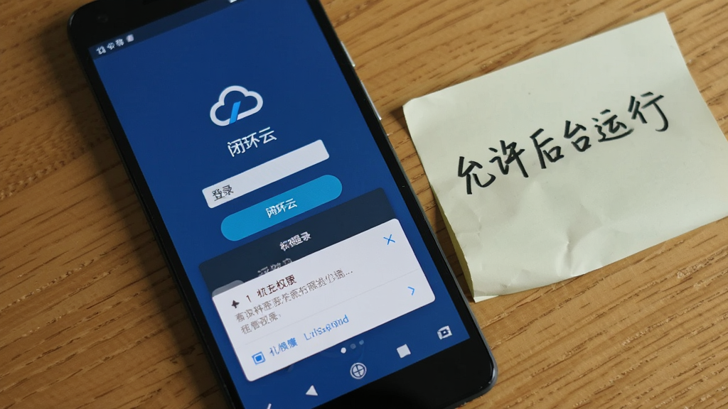 一部安卓手机屏幕显示“闭环云”登录界面,界面下方有权限请求弹窗,手机旁边放着一张手写便签写着“允许后台运行”,背景为木质桌面,风格为生活化写实,光线自然,画质清晰,画面干净无多余物品。